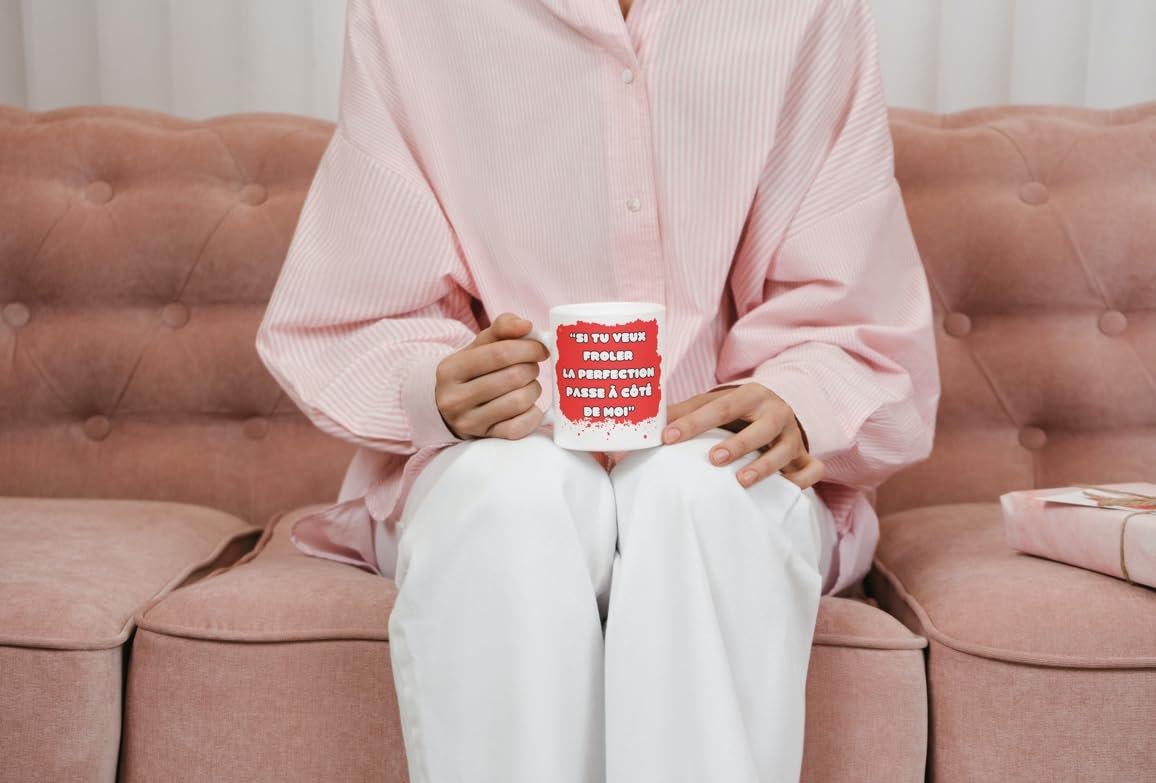 Femme assise sur un canapé rose avec le mug frôler la perfection