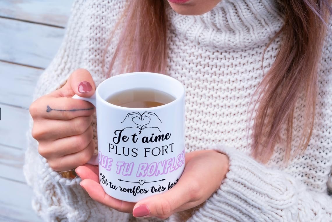 Femme en pull tenant le mug Je t’aime plus fort que tu ronfles
