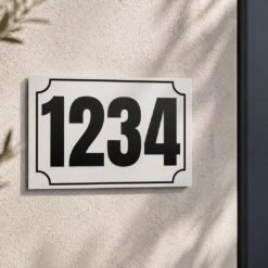 Plaque numéro maison personnalisée blanche avec numéro noir fixée sur un mur extérieur