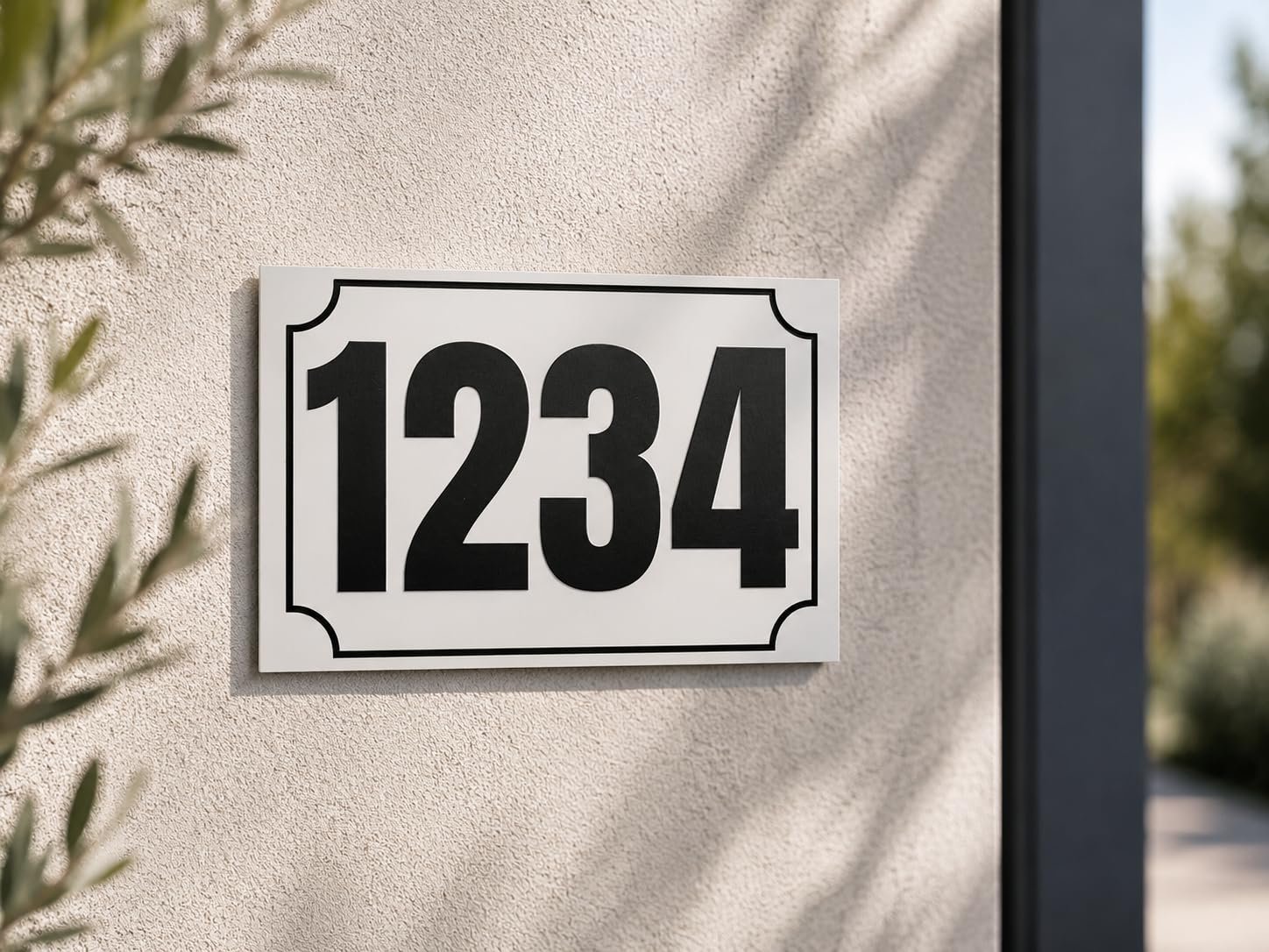 Plaque numéro maison personnalisée blanche avec numéro noir fixée sur un mur extérieur
